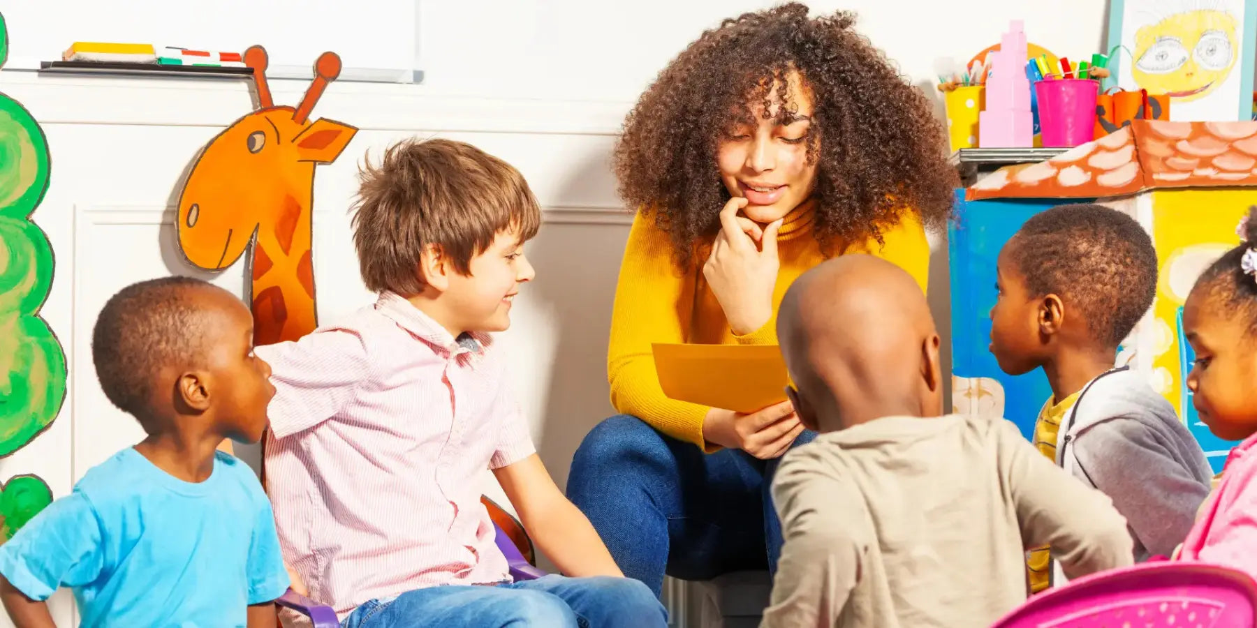 Lehrerin sitzt mit Kindern im Klassenzimmer und liest ein Kinderbuch vor
